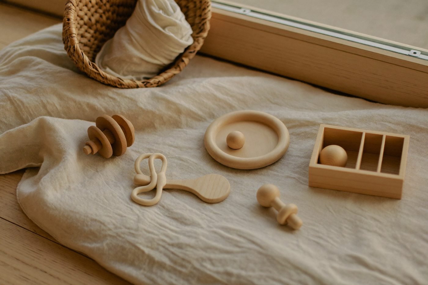 Hochets, anneaux et petits objets en bois disposés sur un lange de lin