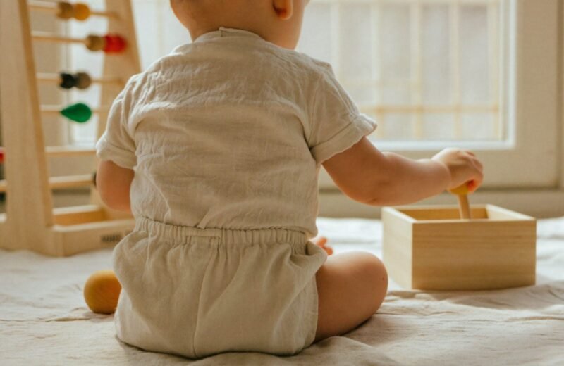 Bébé assis penché au-dessus d'une boîte de permanence de l'objet posée au sol