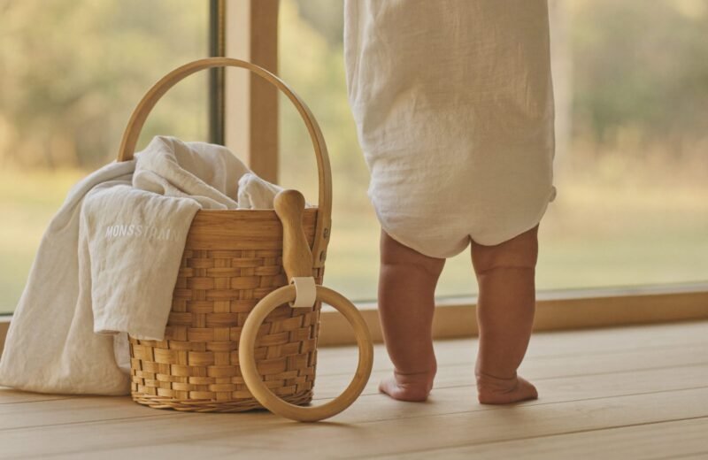 Hochet en bois, balle en tissu et lange posés sur un plaid, cadeau de naissance