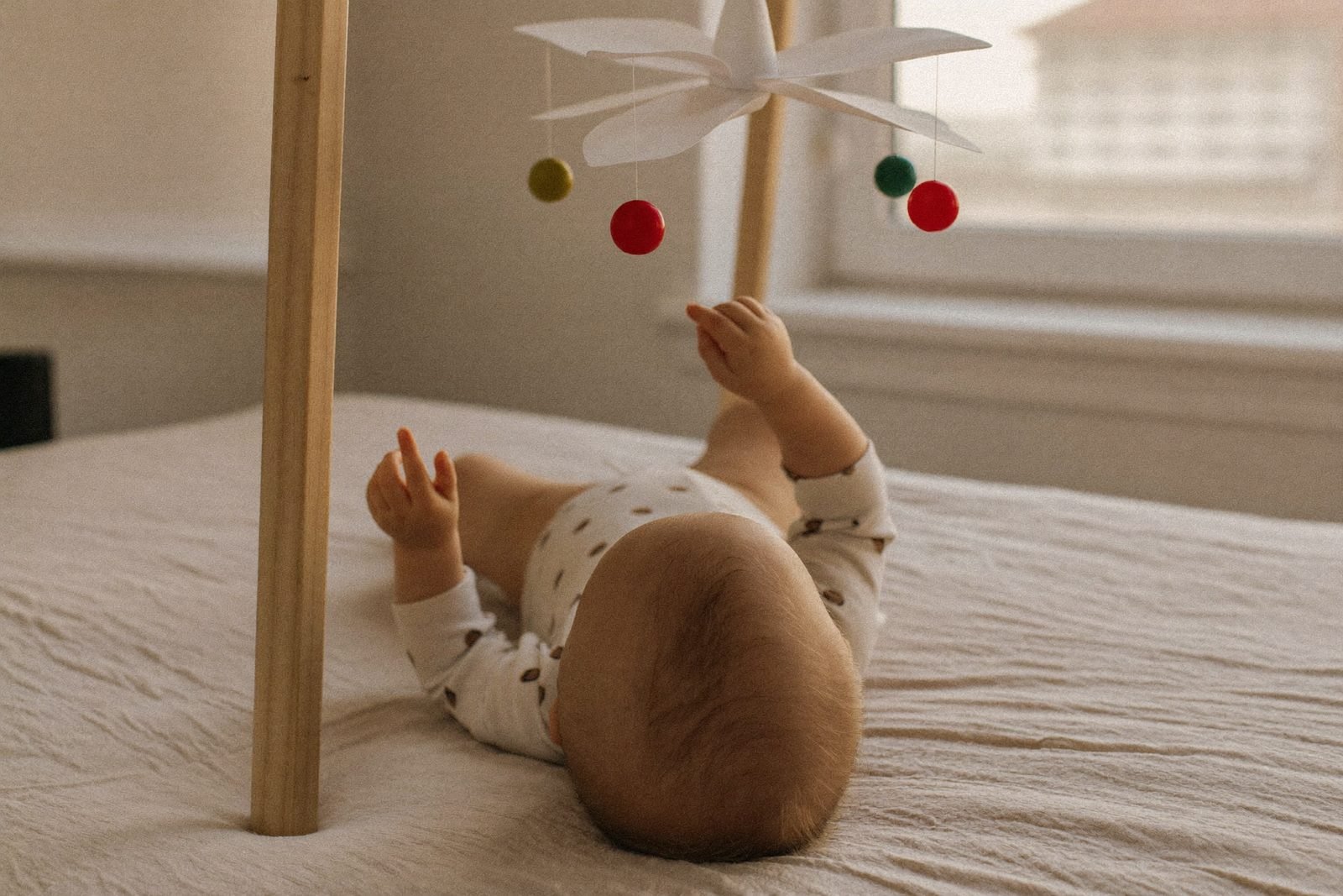 Trois mobiles Montessori suspendus côte à côte, du noir et blanc aux sphères colorées