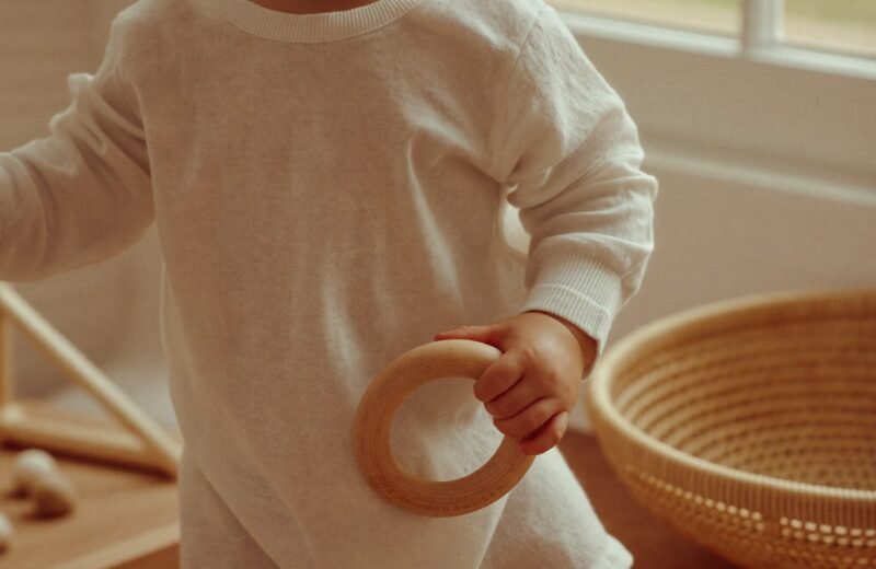 Bébé allongé sur le dos portant un anneau de bois à la bouche