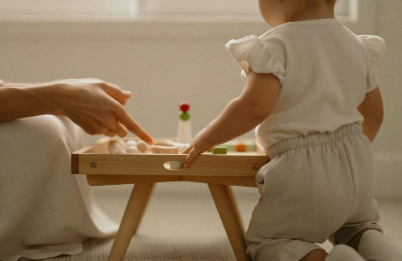 Mains d'adulte présentant lentement un plateau d'activité à un enfant assis