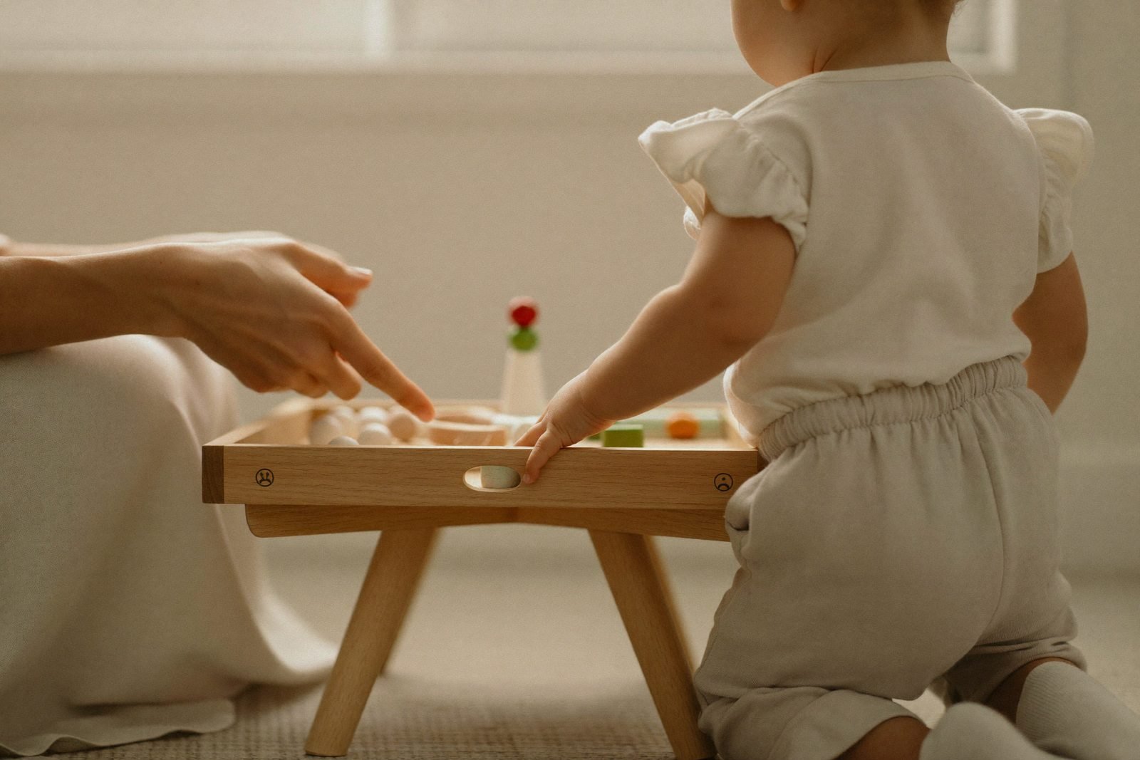 Mains d'adulte présentant lentement un plateau d'activité à un enfant assis
